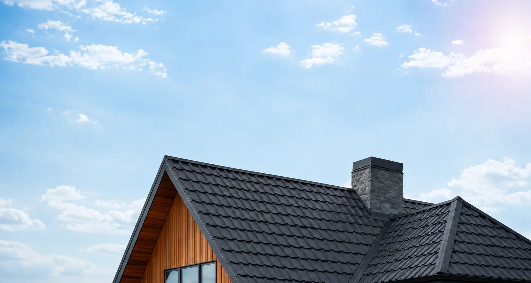 Dark tiled pitched roof of a modern house against a clear blue sky