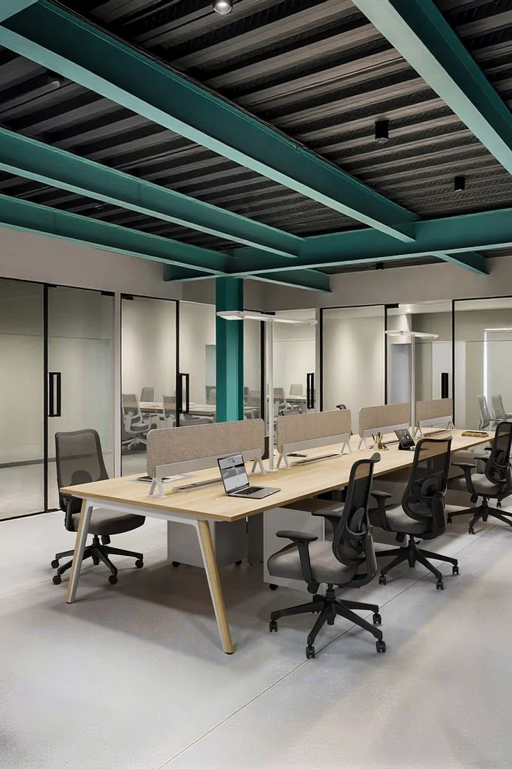 Open workspace with a shared desk run, glass partitions and an exposed teal ceiling grid
