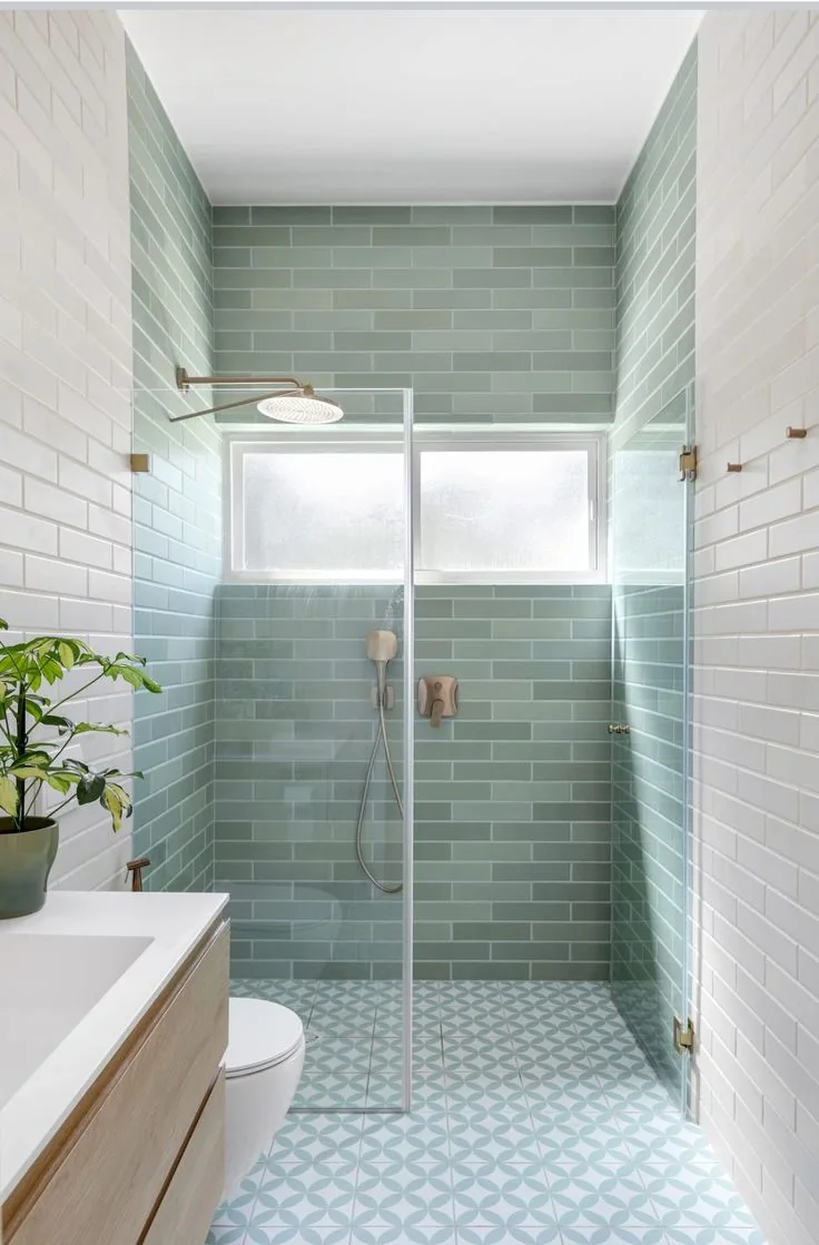 Shower room with green wall tiles and a patterned tile floor